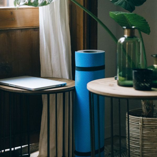 Person rolling out a yoga mat at home by a window.
